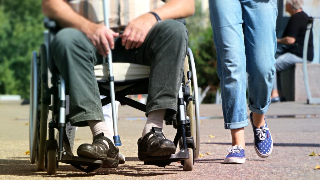 Man i rullstol med assistansperson bredvid